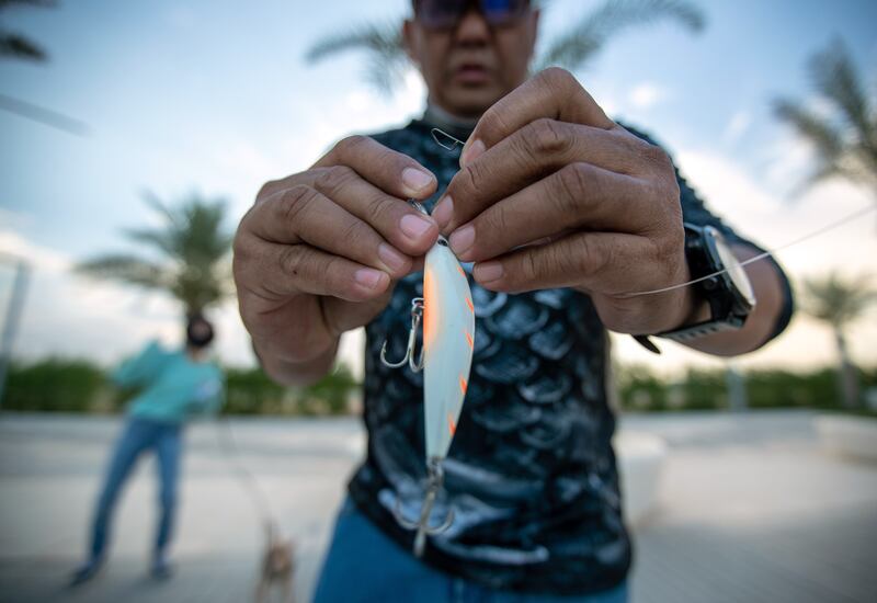 An angler secures a lure to his line.