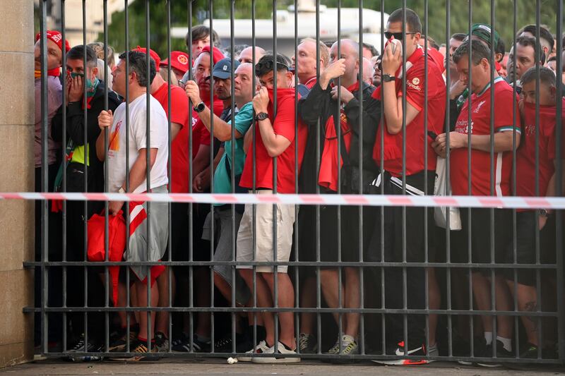 Liverpool fans cover their faces after being sprayed by pepper spray. Getty