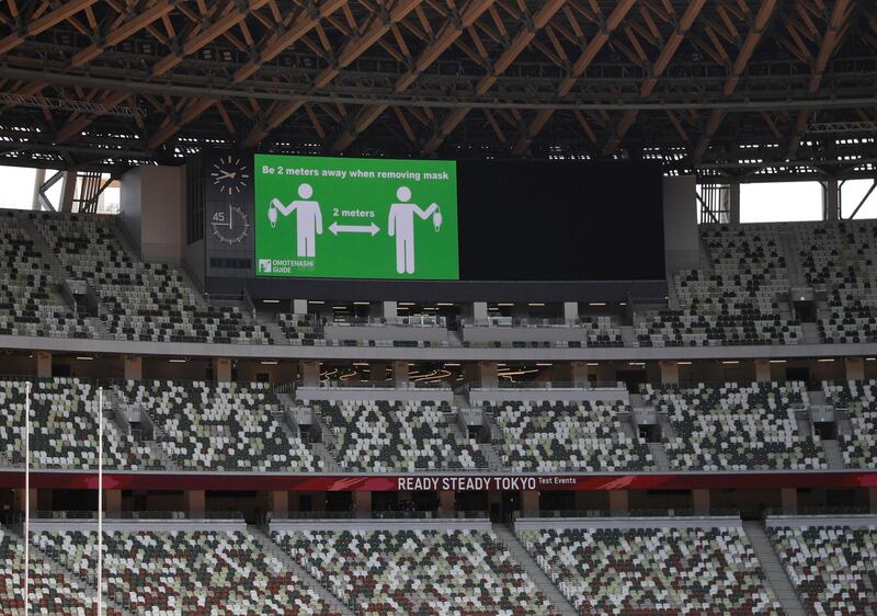 A message regarding safe distancing measures amid the coronavirus pandemic is shown on a screen at the Olympic Stadium before the start of the morning session of the athletics test event. Reuters