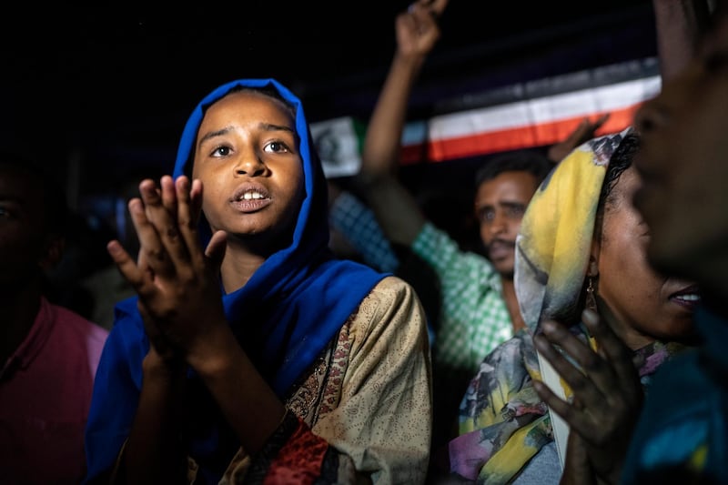 KHARTOUM, SUDAN - APRIL 27: A young girl sings during evening protests against the military junta on April 27, 2019 in Khartoum, Sudan. After months of protesting from the people of Sudan, organised by the Sudanese Professionals' Association (SPA), President Omar al-Bashir was ousted having been in power since 1989. The following day they also forced his successor, Awad Ibn Auf, to step down. The SPA and the people have organised a sit in at the Ministry of Defence calling for the "third fall" of the Transitional Military Council who are currently in charge. (Photo by Fredrik Lerneryd/Getty Images)
