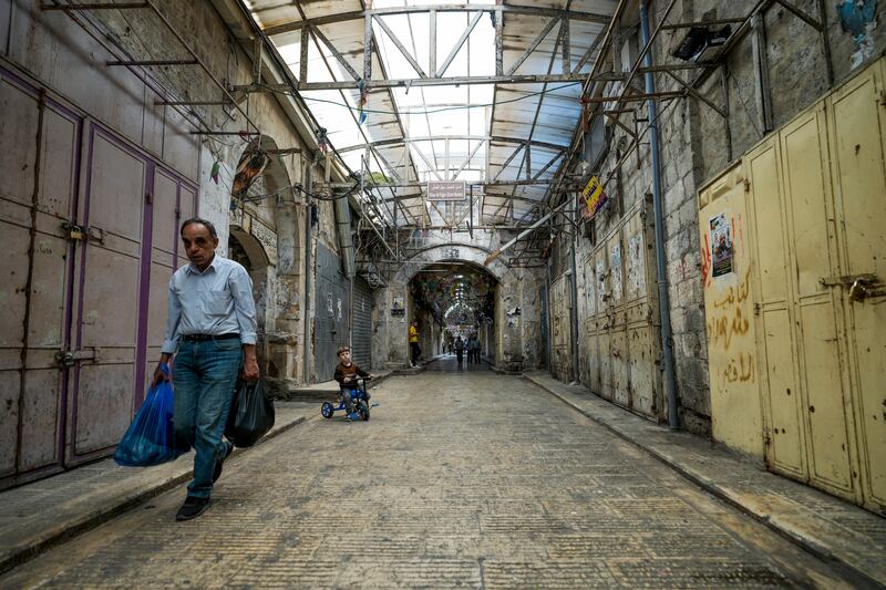 Palestinians walk by closed shops during a general strike. AP