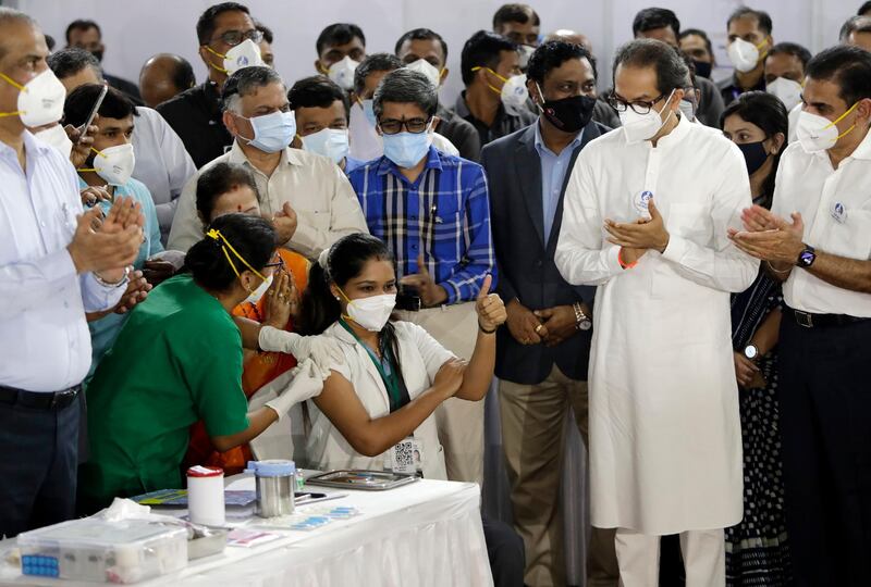 Madhura Patil, a health worker, gestures as she receives the Covid-19 vaccine in the presence of Maharashtra chief minister Uddhav Thackeray, standing beside her, in Mumbai, India. AP Photo