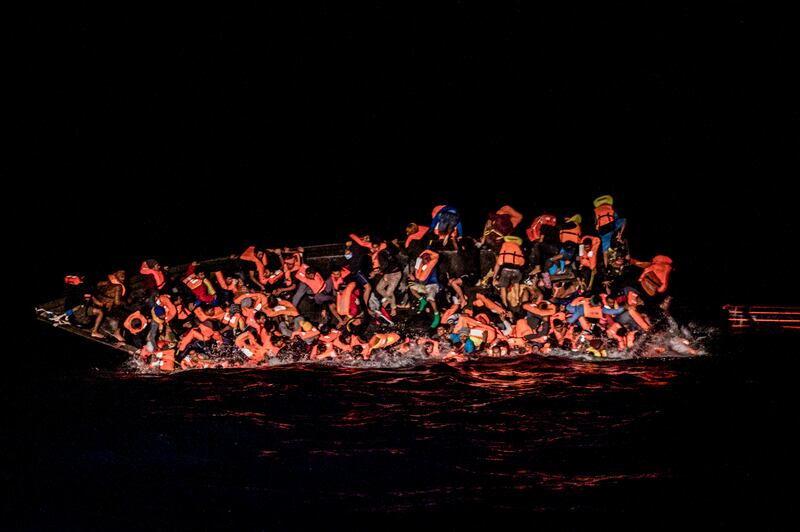 Migrants trying to cling to an upturned boat off Tunisia in May. AP Photo