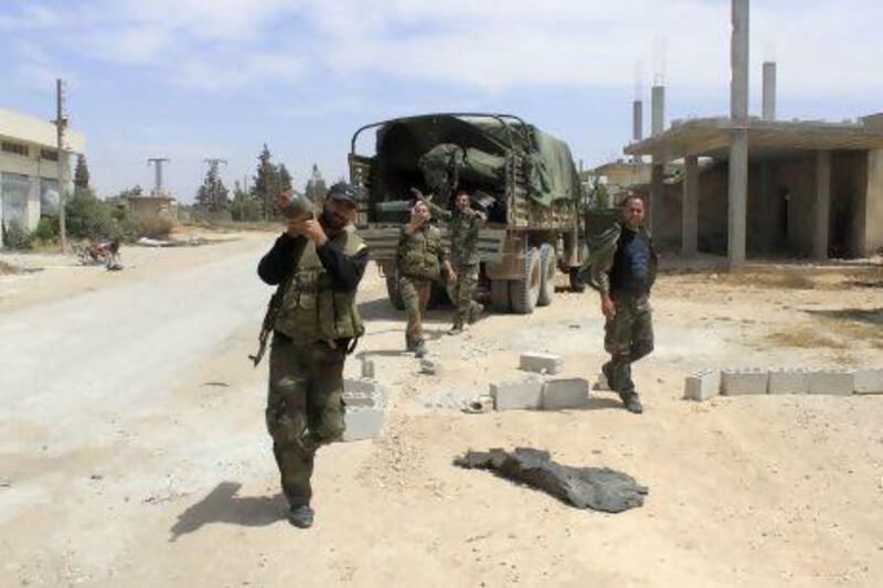 Syrian regime soldiers patrol in Debaa near Qusayr, after the Syrian army took control of the village.