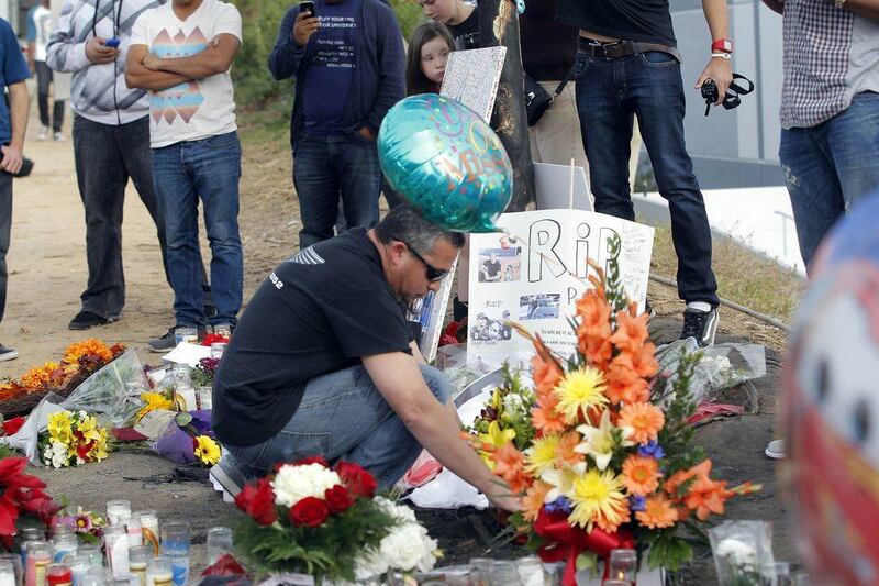 A mourner looks at flowers and memorials at the car crash site that killed actor Paul Walker and another man, north of Los Angeles Nick Ut / AP Photo
