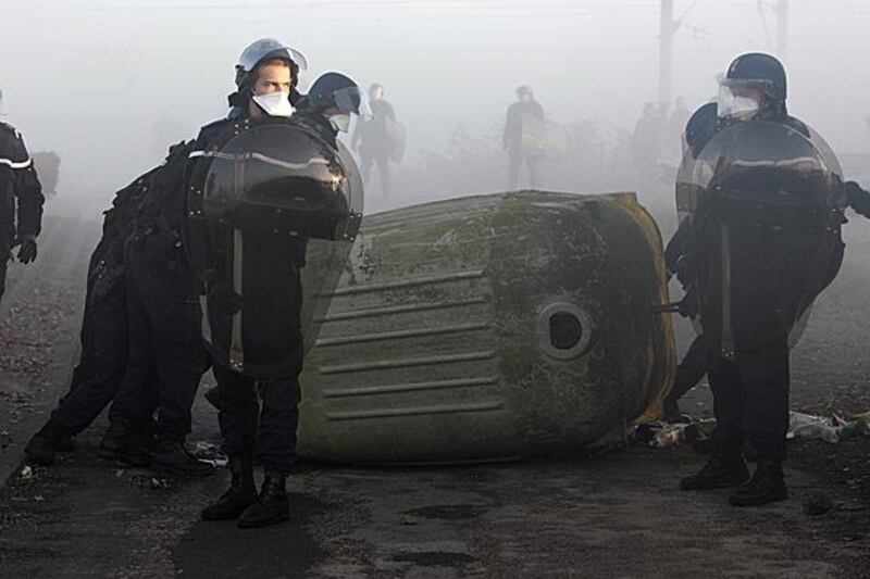 French gendarmes (military police) block the acces to the railway tracks as anti-nuclear demonstrators protest against a planned castor container tranport of nuclear waste, on November 23, 2011 in the French western city of Flottemanville. According to Greenpeace and the French nuclear phaseout initiative "Sortir du Nucleaire" (Out of the Nuclear Power), eleven castors containing nuclear waste will leave the freight station in the city of  Valognes, western France, a day earlyer than expected, on Wednesday, November 23, 2011, to be transported to the deposit in Gorleben. Banner reads : "Nuclear waste : dead end." AFP PHOTO / KENZO TRIBOUILLARD

