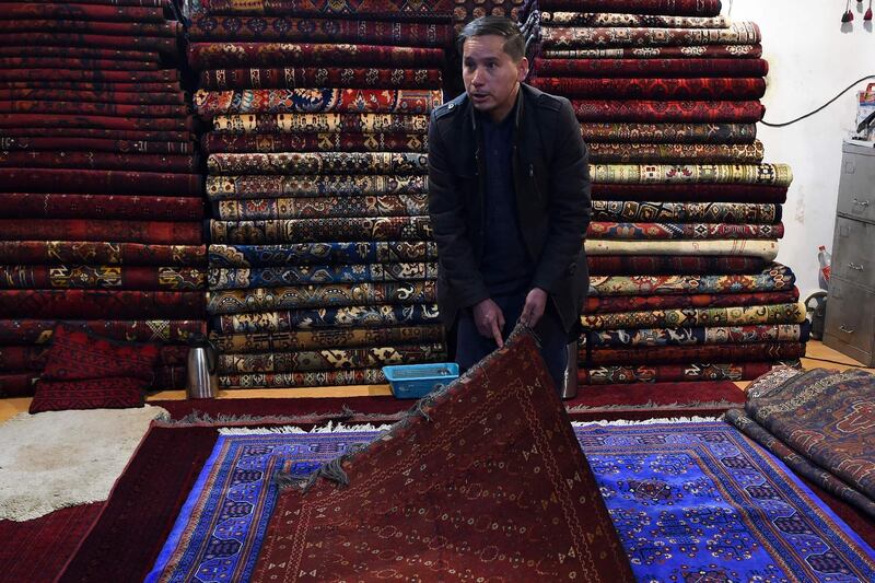 Rug hunter Chari Allahqul shows off his collection at his shop on Chicken Street in Kabul. AFP