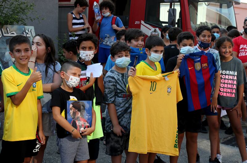 Children hold pictures of Ronaldinho and football shirts as they eagerly await the arrival of the Brazilian sports star.