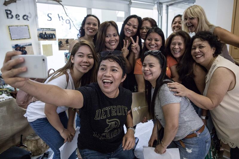 In this picture taken on September 3, 2017, Joy Carbonell takes a selfie with fellow members of the "Unsung Heroes" choir, a group of Filipina domestic workers, during a practice session inside a kindergarten school's classroom in Hong Kong.
Each Sunday, a choir of Filipina domestic workers in Hong Kong gathers to sing songs that remind them of the children they left back home. Known as the "Unsung Heroes", what began as a group of shy performers now regularly take the stage around Hong Kong and feature in a new documentary about the lives of the city's maids, known locally as "helpers". / AFP PHOTO / DALE DE LA REY / To go with AFP story Hong Kong-Philippines-music-social-film-maids , Feature by Laura Mannering