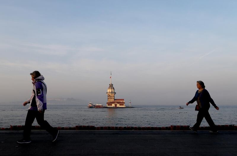 People walk in front of the Maiden's Tower on a foggy day by the Bosphorus in Istanbul.  EPA