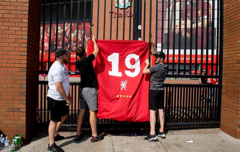 Liverpool fans hang up a celebratory banner on a fence outside Anfield stadium. EPA