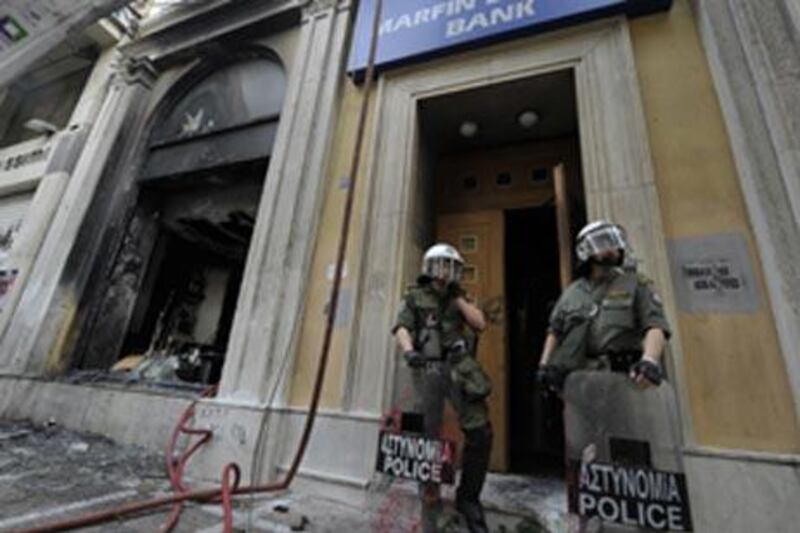 Riot police in front of the burnt out Marfin Egnatia Bank, Athens, where three people were killed in a firebomb attack during massive rioting.