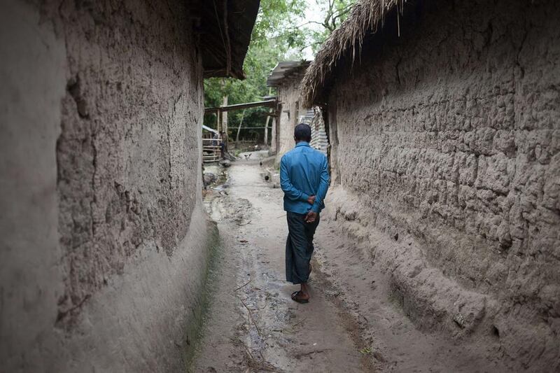 A Bangladeshi villager walks between homes in the village of Kalai. Suvra Kanti Das / AFP