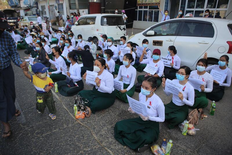 Schoolteachers hold up posters during a sit-down demonstration against the February 1 military coup in Yangon. AFP