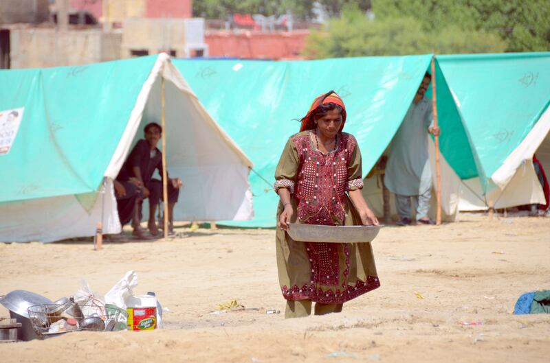 A pregnant woman carries water as she take a refuge at a camp in Jaffarabad. AP