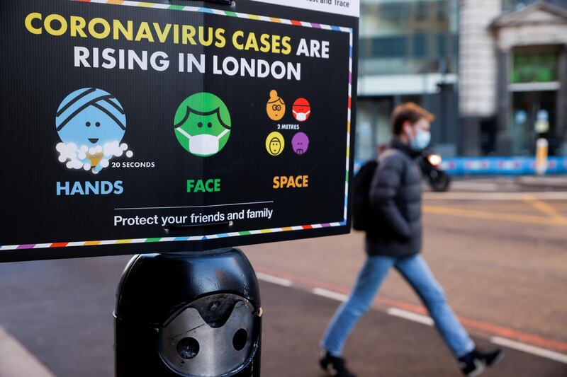 A man wearing a face mask walks past a government sign with instructions about COVID-19 amid the coronavirus disease (COVID-19) outbreak, in London, Britain, January 25, 2021. REUTERS/John Sibley