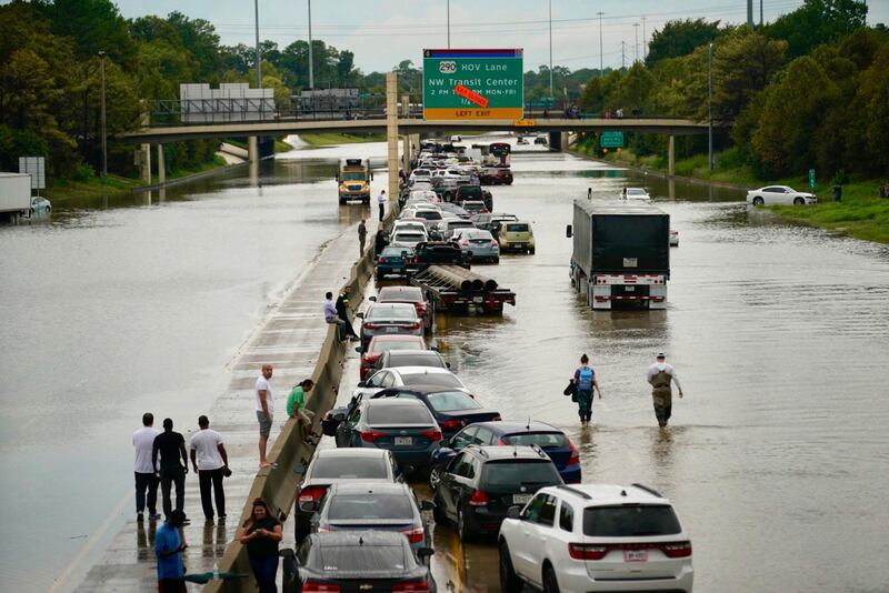 People wait outside of their stranded vehicles along Interstate 10 westbound at T.C Jester, Thursday, Sept. 19, 2019. The freeway is closed because of high water east bound on the freeway. (Mark Mulligan/Houston Chronicle via AP)
