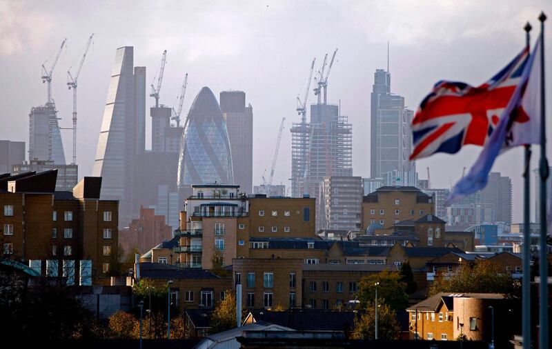 (FILES) In this file photo taken on October 21, 2017 A Union flag flies from a pole as construction cranes stand near skyscrapers in the City of London, including the Heron Tower, Tower 42, 30 St Mary Axe commonly called the "Gherkin", the Leadenhall Building, commonly called the "Cheesegrater", as they are pictured beyond blocks of residential flats and apartment blocks, from east London on October 21, 2017. Britain will slide into a year-long recession should it leave the European Union without a deal with Brussels, the government's official forecaster said on July 18, 2019. / AFP / Tolga AKMEN
