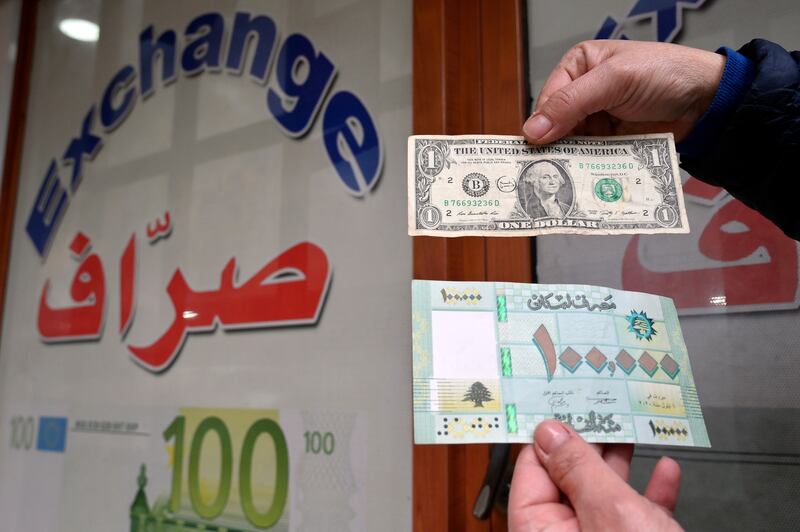 A person shows bank notes - one US dollar and 100,000 Lebanese Lira. The IMF has recommended that the government's multiple official exchange rates be unified. EPA