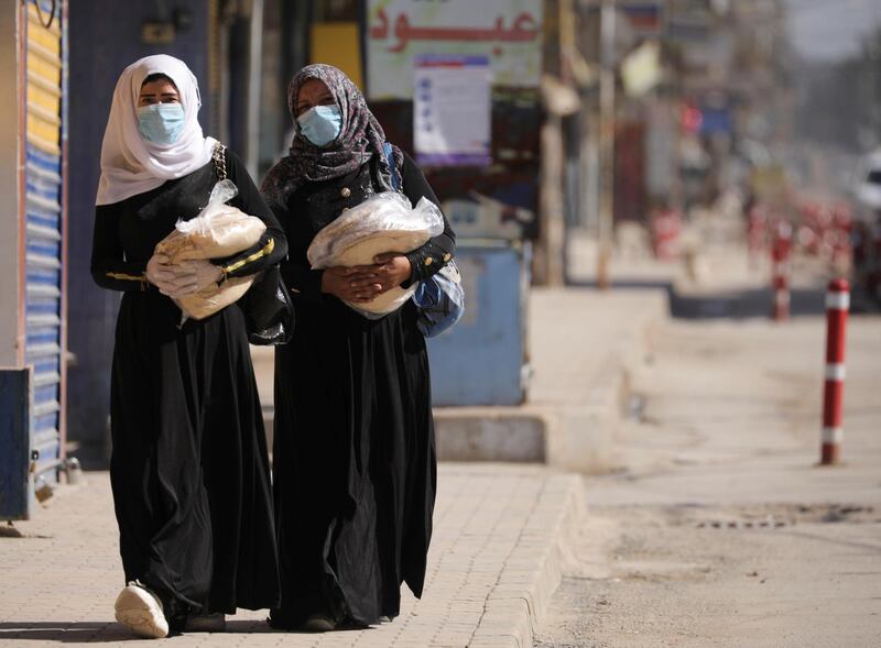 Women hold stacks of bread as they walk along an empty street, as restrictions are imposed as a measure to prevent the spread of the coronavirus disease (COVID-19) in Qamishli, Syria. Reuters