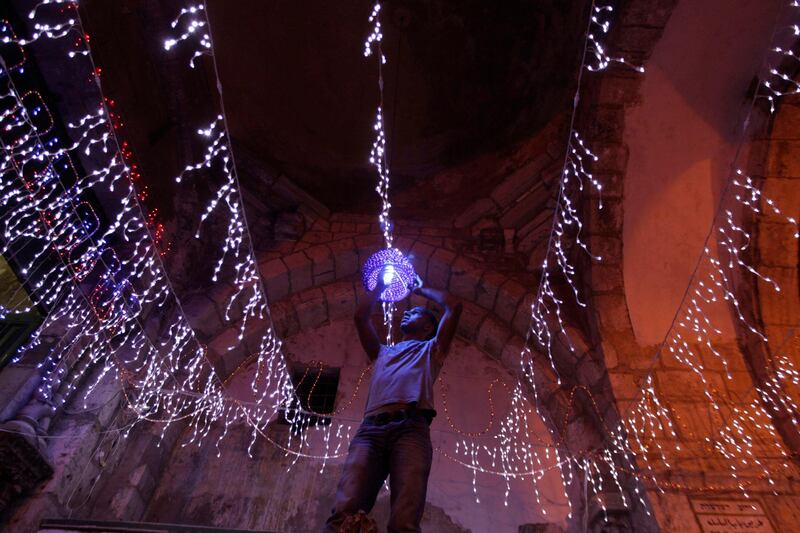 A Palestinian man hangs decorations for the upcoming holy month of Ramadan outside his home in Jerusalem's Old City July 31, 2011. Muslims around the world abstain from eating, drinking and conducting sexual relations from sunrise to sunset during Ramadan, the holiest month in the Islamic calendar. REUTERS/Ammar Awad (JERUSALEM - Tags: RELIGION IMAGES OF THE DAY) *** Local Caption ***  JER11_PALESTINIANS-_0731_11.JPG