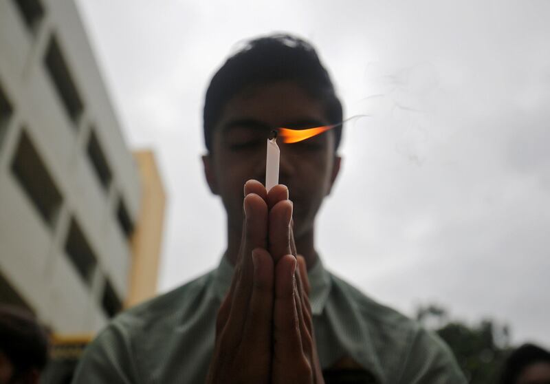 A schoolboy holds a candle as he prays inside a school in Ahmedabad, India, to pay tribute to Hindu pilgrims who were killed in a gun battle that erupted in Kashmir today. Reuters / Amit Dave