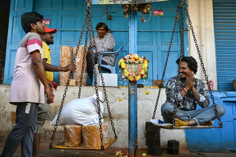 A man sits on a weighing scale to buy unrefined sugar equal to his weight to worship tribal Hindu deities ahead of the Medaram Jatara festival, in Hyderabad, India. AFP