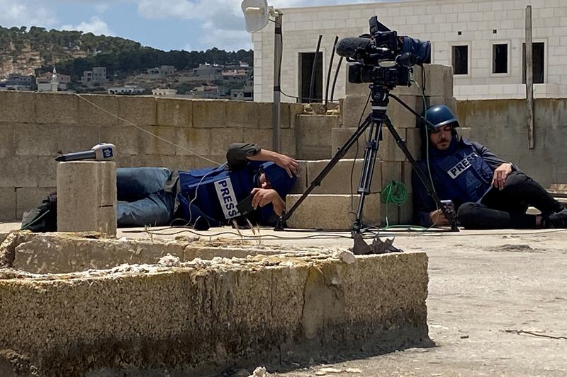 Palestinian journalists take cover on a rooftop while covering the Israeli raid. Reuters