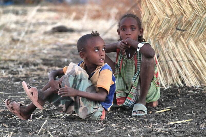 A picture taken on Coptic Christmas eve shows Ethiopian children sitting outside their family's tent at Um Raquba refugee camp in Gedaref, eastern Sudan, on January 6, 2021. (Photo by ASHRAF SHAZLY / AFP)