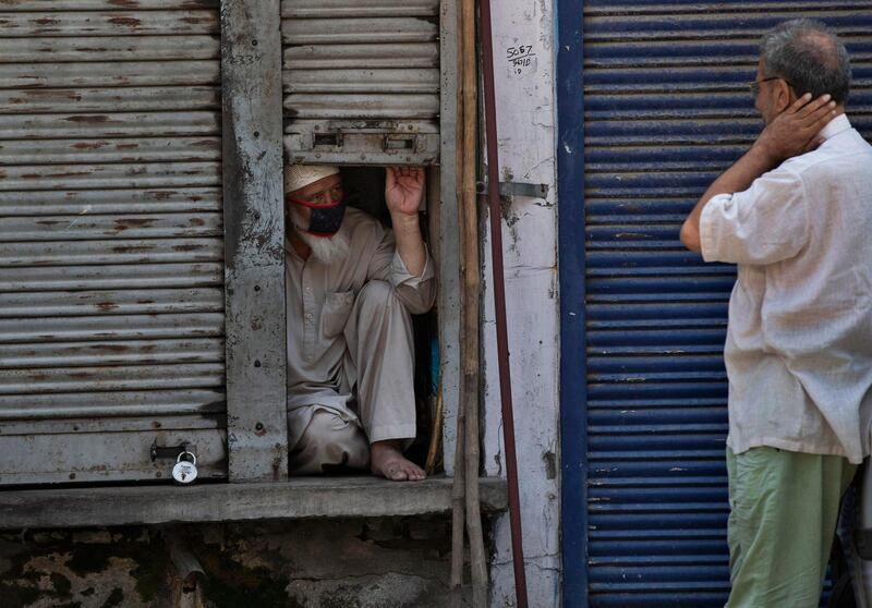 A Kashmiri shopkeeper chats with his neighbor from a half closed shop during a lockdown in Srinagar, Indian controlled Kashmi. AP Photo