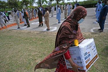 A woman in need carries foodstuff being distributed by the embassy of United Arab Emirates ahead of Ramadan in Islamabad on April 12, 2021. / AFP / Aamir QURESHI