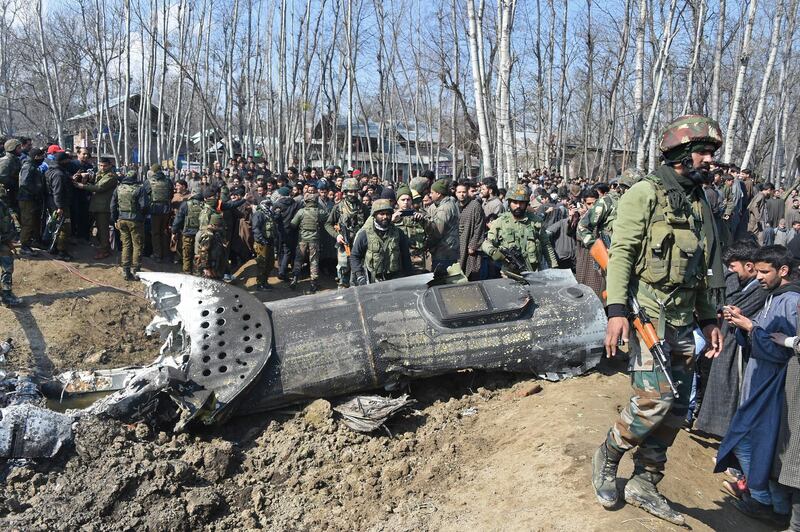 Indian soldiers and Kashmiri onlookers stand near the remains of an Indian Air Force aircraft after it crashed in Budgam district, 30 km from Srinagar. AFP