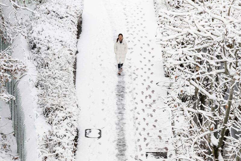 A woman walks along a footpath after snowfall in Seoul. AFP