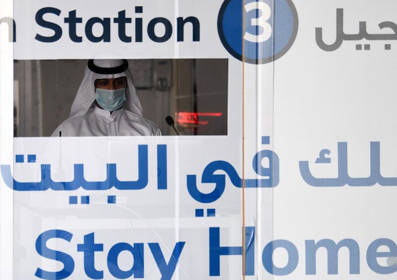 A medical worker in a booth prepares to swab residents at a drive-through test centre in the Dubai suburb of Khawaneej. AFP