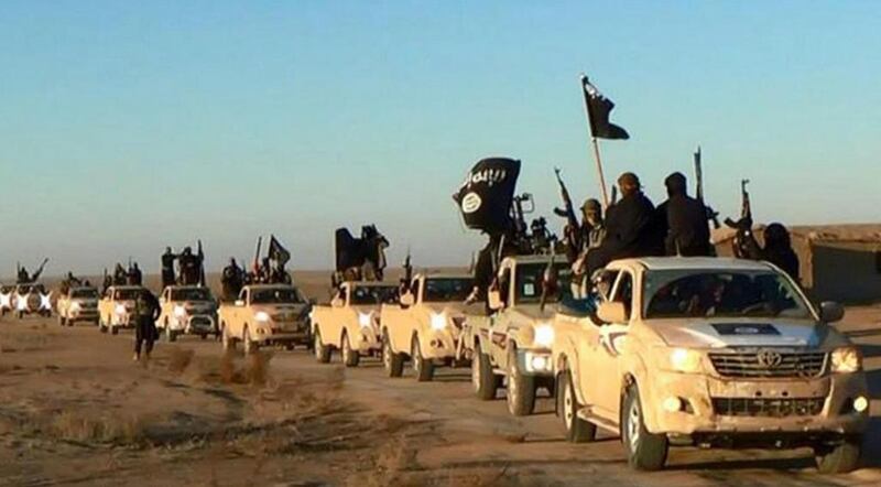 A file image of ISIS militants holding up their weapons and wave flags as they ride in a convoy near Raqqa city. AP