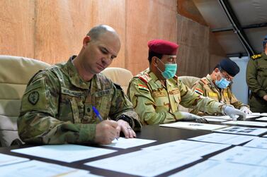 US army commander Jace Neuenschwander (L) and Iraq Nineveh Operations Commander Major General Noman Zawbai (C) sign documents during a handover ceremony at a base for the US-led coalition, in Mosul in the northern Iraqi province of Nineveh on March 30, 2020. AFP 