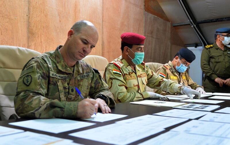 US army commander Jace Neuenschwander (L) and Iraq Nineveh Operations Commander Major General Noman Zawbai (C) and Iraq’s Staff Major General Mohammad Fadhel Abbas sign documents during a handover ceremony at a base for the Combined Joint Task Force – Operation Inherent Resolve (CJTF-OIR), the US-led coalition against the Islamic State (IS) group, in Mosul in the northern Iraqi province of Nineveh during a handover ceremony to Iraqi forces on March 30, 2020. The US-led coalition is temporarily withdrawing training forces from Iraq as a protective measure against the novel coronavirus, a senior official in the alliance said on Thursday.  / AFP / Zaid AL-OBEIDI
