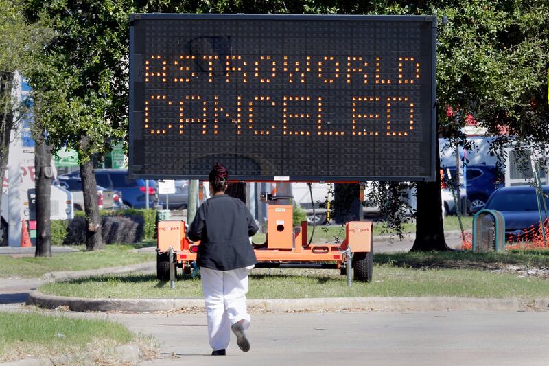 A pedestrian crosses Main Street in front of a sign announcing the cancellation of Astroworld. AP
