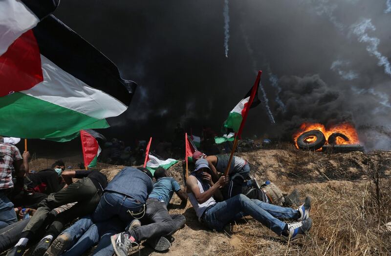 Palestinian demonstrators take cover from Israeli fire and tear gas during a protest against U.S. embassy move to Jerusalem and ahead of the 70th anniversary of Nakba, at the Israel-Gaza border in the southern Gaza Strip May 14, 2018. REUTERS/Ibraheem Abu Mustafa