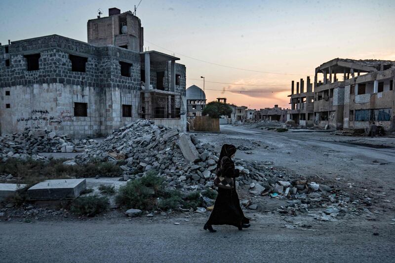 A Syrian woman walks past destruction in the northern Syrian city of Raqqa.