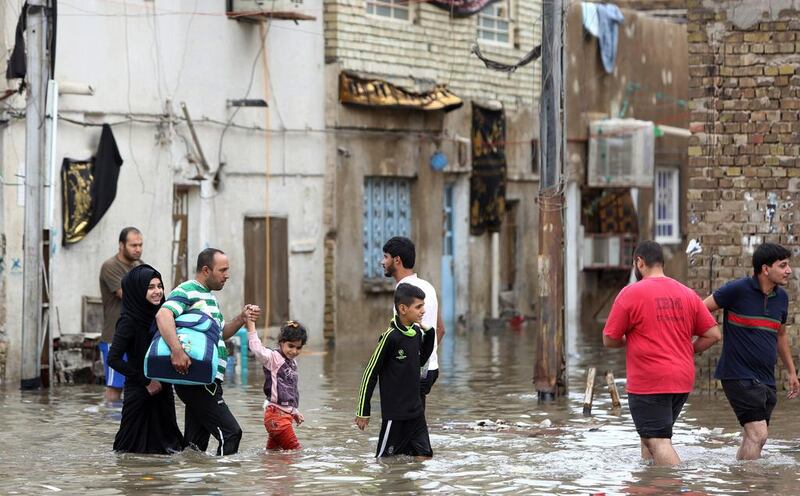 Iraqis walk in a flooded street after heavy rainfall in the capital Baghdad. Ahmad Al Rubaye / AFP Photo 