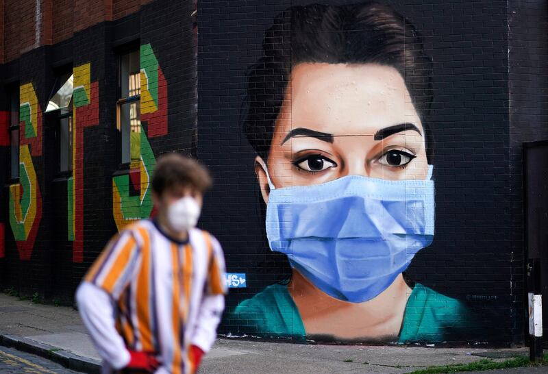A man wearing a protective mask walks past a mural depicting a nurse in Shoreditch, amid the coronavirus disease (COVID-19) outbreak, in London, Britain. REUTERS