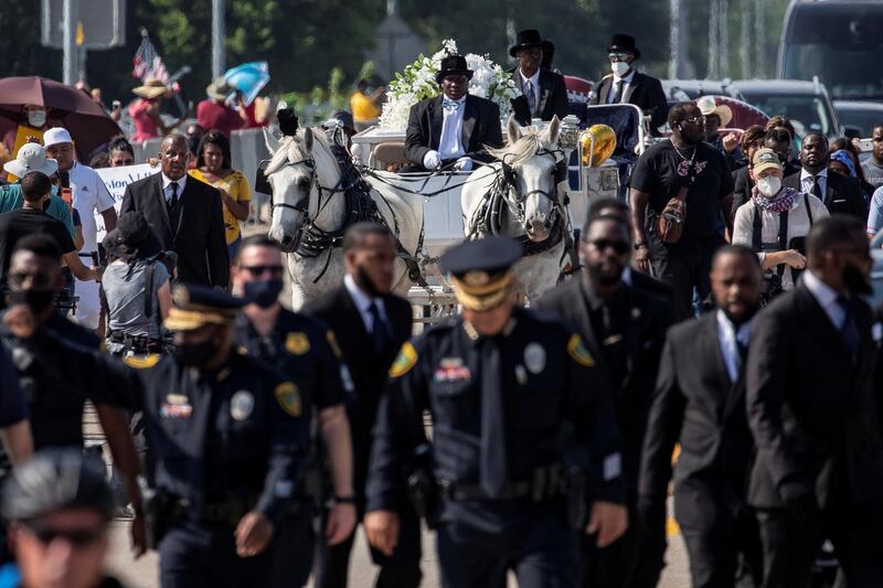A row of police officers walk ahead of the horse-drawn carriage coffin of George Floyd, whose death in Minneapolis police custody has sparked nationwide protests against racial inequality. Reuters