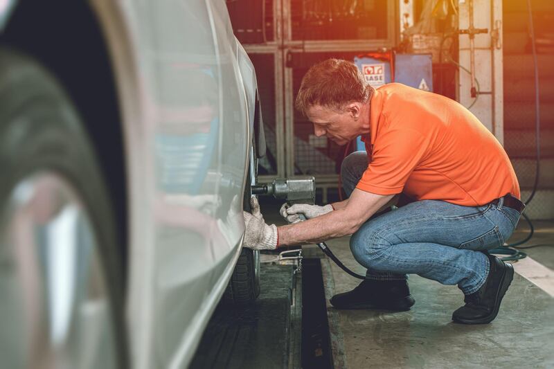 2DYAMH3 Auto mechanic worker service car by checking inflate or change tires in garage automobile workshop. Alamy