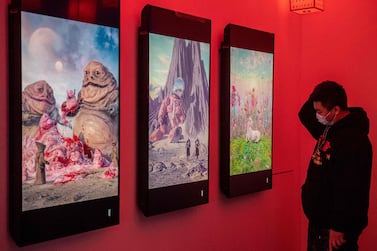 A man looks at digital paintings by US artist Beeple at crypto art exhibition Virtual Niche: Have You Ever Seen Memes in the Mirror?, one of the world's first physical museum shows of blockchain art in Beijing in March. AFP