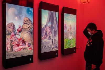 A man looks at digital paintings by US artist Beeple at a crypto art exhibition entitled “Virtual Niche: Have You Ever Seen Memes in the Mirror?”, one of the world's first physical museum shows of blockchain art, ahead of its opening in Beijing on March 26, 2021. RESTRICTED TO EDITORIAL USE - MANDATORY MENTION OF THE ARTIST UPON PUBLICATION - TO ILLUSTRATE THE EVENT AS SPECIFIED IN THE CAPTION
 / AFP / NICOLAS ASFOURI / RESTRICTED TO EDITORIAL USE - MANDATORY MENTION OF THE ARTIST UPON PUBLICATION - TO ILLUSTRATE THE EVENT AS SPECIFIED IN THE CAPTION
