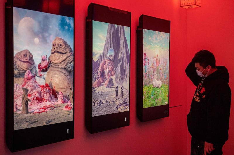 A man looks at digital paintings by US artist Beeple at a crypto art exhibition entitled “Virtual Niche: Have You Ever Seen Memes in the Mirror?”, one of the world's first physical museum shows of blockchain art, ahead of its opening in Beijing on March 26, 2021. RESTRICTED TO EDITORIAL USE - MANDATORY MENTION OF THE ARTIST UPON PUBLICATION - TO ILLUSTRATE THE EVENT AS SPECIFIED IN THE CAPTION
 / AFP / NICOLAS ASFOURI / RESTRICTED TO EDITORIAL USE - MANDATORY MENTION OF THE ARTIST UPON PUBLICATION - TO ILLUSTRATE THE EVENT AS SPECIFIED IN THE CAPTION
