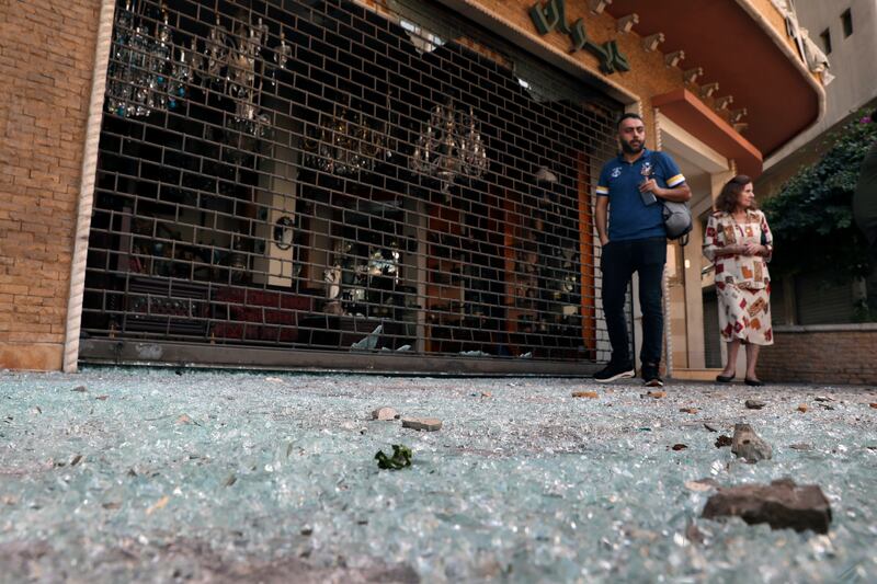 People walk on glass from broken windows littering a street after the violence. AP