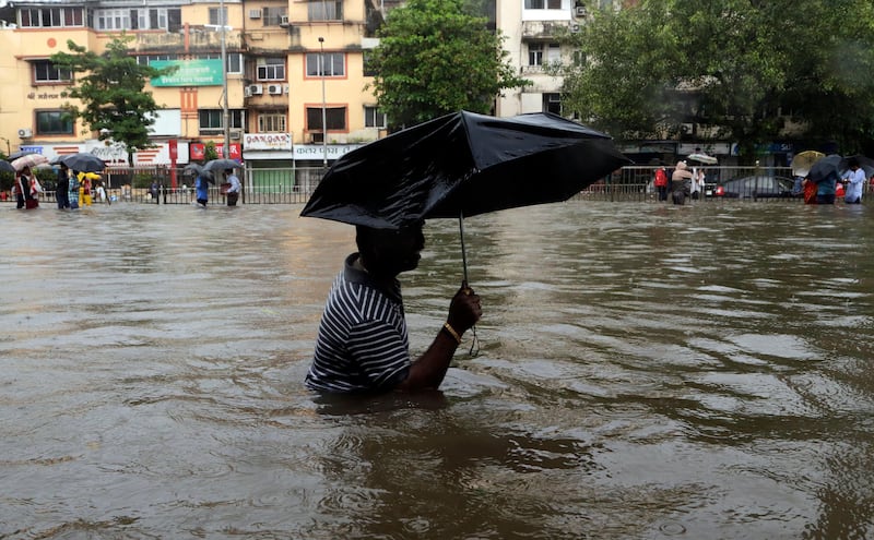 A man wades through a waterlogged street following heavy rains in Mumbai. Rajanish Kakade / AP Photo