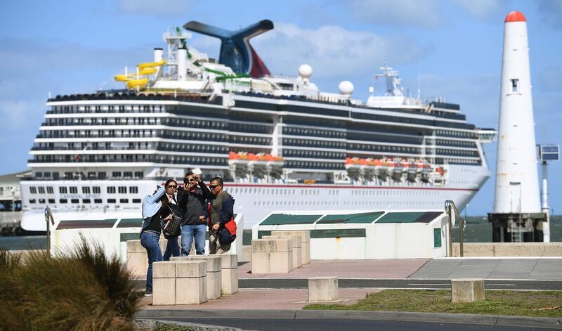 Tourists taking photos in front  of a cruise liner docked at Station Pier as Australian Prime Minister Scott Morrison on March 15 announces all cruise ships will be banned entirely from docking in Australia. AFP